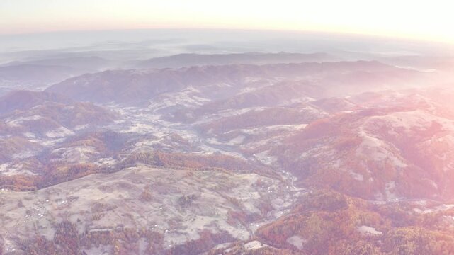 Ukraine, drone, flight in the Carpathians early in the autumn morning at sunrise near the city of Kosiv. Bright forests and dwellings of the Hutsul highlanders on the glades
