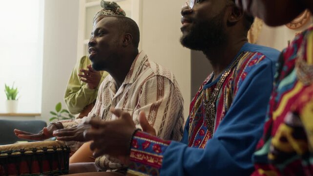 Four positive Black young friends playing djembes and singing when celebrating African identity and social values