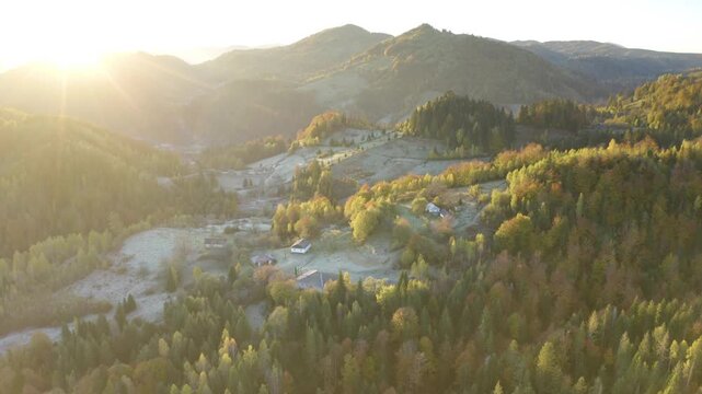 Ukraine, drone, flight in the Carpathians early in the autumn morning at sunrise near the city of Kosiv. Bright forests and dwellings of the Hutsul highlanders on the glades