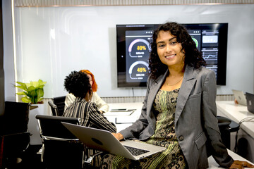 Portrait of young happy businesswoman with curly hair looks at camera during meeting. Beautiful...