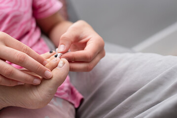A caregiver carefully tends to a child’s toes during a home pedicure moment. A girl takes care of her mother's feet, gives her new pedicure, removes old nail polish
