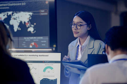 Customer success analyst tracks satisfaction KPIs NPS dashboard reveals insights Asian pro female glasses tablet stylus reviews feedback trends modern global operations center achieve goals now boost.