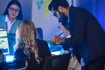 In a Security Operations Center, a dedicated diverse incident response team male and female in uniform analyzes live CCTV feeds on a video wall