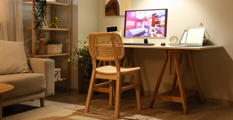 Computer with launched video game on table in stylish living room at evening