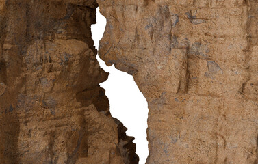 A rugged, textured rock wall in warm earth tones features a deep, jagged, vertical black crack cutting through its surface, suggesting a geological fissure