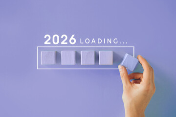 Hand placing a final block in a progress bar labeled 2026 LOADING, concept of anticipation, future...