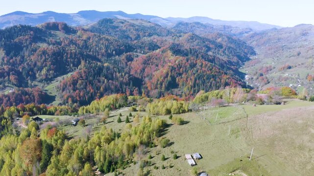 Ukraine, drone, flight in the Carpathians early in the autumn morning at sunrise near the city of Kosiv. Bright forests and dwellings of the Hutsul highlanders on the glades