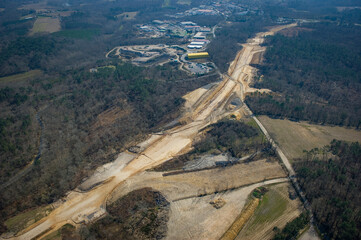 Construction crews work on a high-speed train line in France, creating a path through the landscape while a highway runs parallel.