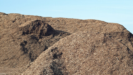 a mountain of wood chips against a blue sky close-up