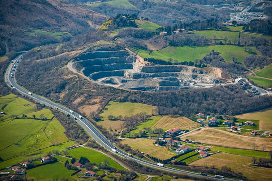 Aerial view of the Urugne area showcasing green fields, a quarry site, and a highway. The landscape features a mix of rural and developed areas, highlighting the natural beauty of the region.