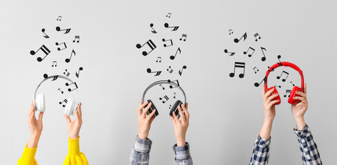 Hands with modern headphones on light background
