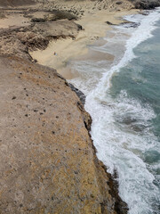Aerial view of rocky volcanic coastline near Playa Blanca, southern Lanzarote, with clear Atlantic waters and arid desert terrain.
