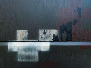 Abstract industrial background featuring reflections of geometric shapes on a dark, dirty metallic surface with subtle patches of rust and paint, conveying urban decay.