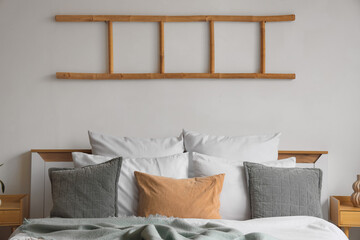 Interior of light bedroom with big bed and ladder