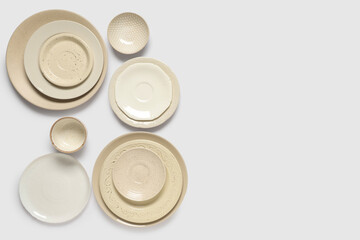 Set of beige plates and bowls on white background
