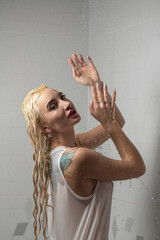 Woman with long blonde hair, enjoying a refreshing shower, water cascading down her body, in a modern bathroom with geometric tiles, showcasing relaxation and self-care