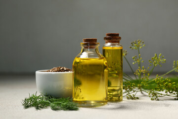 Bottles of dill oil with seeds on grey grunge background