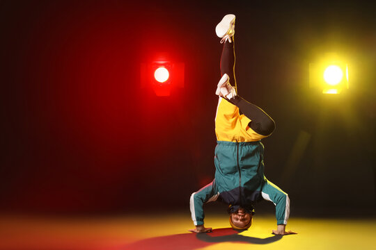 Handsome young man dancing hip-hop on dark color background - Powered by Adobe