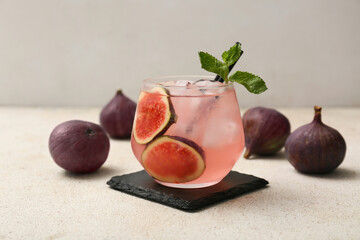 Glass of fresh fig lemonade on white grunge table, closeup