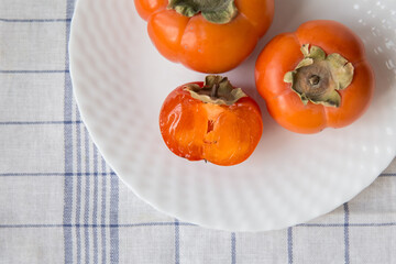 Close-up of three persimmons on a white plate
