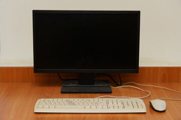 Desktop computer setup with monitor, keyboard, and mouse in a plain workspace