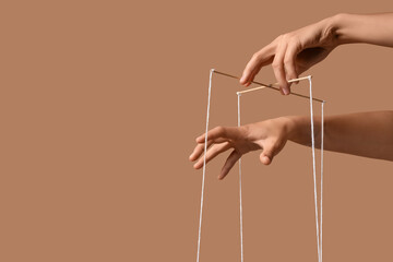 Female hands of puppeteer with strings on beige background