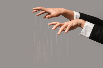 Female hands of puppeteer with strings on grey background
