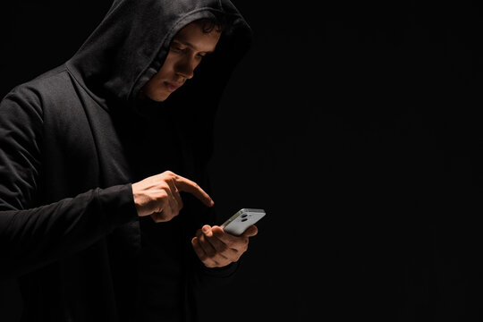 Male fraudster using mobile phone on black background