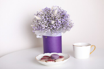 
Cup of tea and berry macarons, bouquet of violet flowers