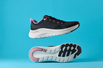 Black and pink running shoes levitating on a vibrant blue background, showcasing dynamic footwear design and athletic potential