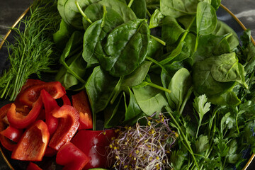 Bowl with fresh vegetables and greens &mdash; spinach, red bell pepper, cucumber, dill and sprouts. Healthy eating, vegetarian food, detox and fitness diet concept.