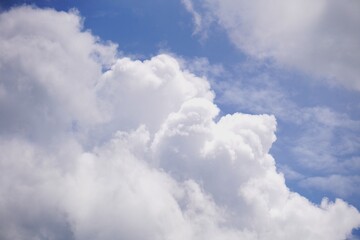Fluffy white cumulus clouds floating in a bright blue summer sky.