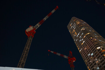 夜のタワークレーンと高層マンション