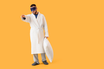 Male sleepwalker with pillow on yellow background