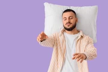Male sleepwalker in pajamas with pillow on lilac background