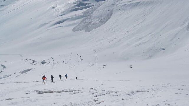 Alpinists group snowy descending Lenin Glacier from Camp 2 5300m with vast panoramic view of "Frying Pan" in Pamir mountains Plateau. Active people concept. Lenin peak expedition route in Kyrgyzstan