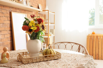 Vase with autumn flowers and pumpkins on dining table in room