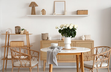 Interior of light room with white roses in vase on dining table