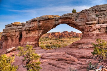 Arches Nationalpark, Moab in Utah US.. sunlit red rock desert landscape reveals towering sandstone spires and eroded fins under clear azure sky.