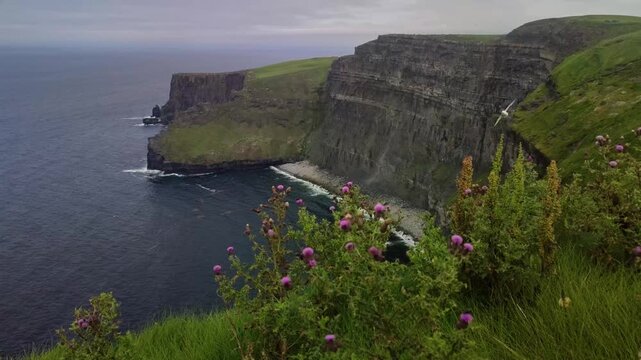 Scenic view of the Cliffs of Moher in Ireland with rugged coastline and cloudy sky.