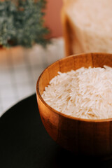 Long grain white rice in a wooden bowl on a black plate with a decorative background
