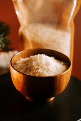 Long grain white rice in a wooden bowl with a packing bag in background