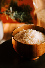 Long grain white rice presented in a wooden bowl on a kitchen table in warm lighting