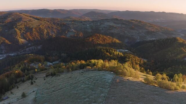 Ukraine, drone, flight in the Carpathians early autumn morning at sunrise near the city of Kosiv. Bright forests and frost of the night frost