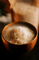 Long grain white rice served in a wooden bowl with grains in focus and a blurred bag behind