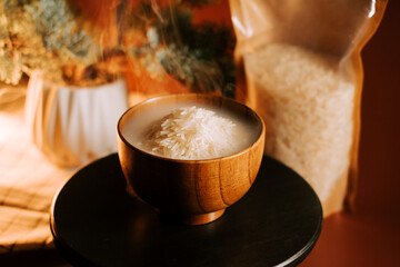 Long grain white rice served in a wooden bowl with steam rising in a cozy kitchen setting