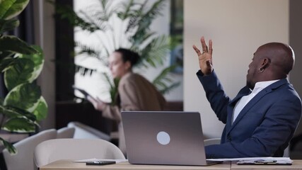 A businessman and a businesswoman have a joint discussion while looking at data on a laptop in a modern office.