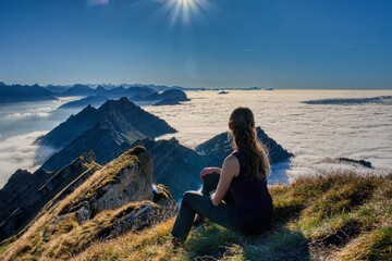 A young woman on the Speer mountain enjoys the view of the sea of ​​fog and the surrounding mountains. Hiking in Switzerland. Near Glarus and Toggenburg. High quality photo.