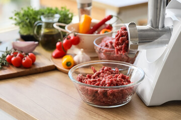 Modern meat grinder with minced beef on table in kitchen, closeup