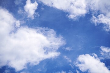Fototapeta premium Bright blue sky with fluffy white cumulus clouds on a sunny day.